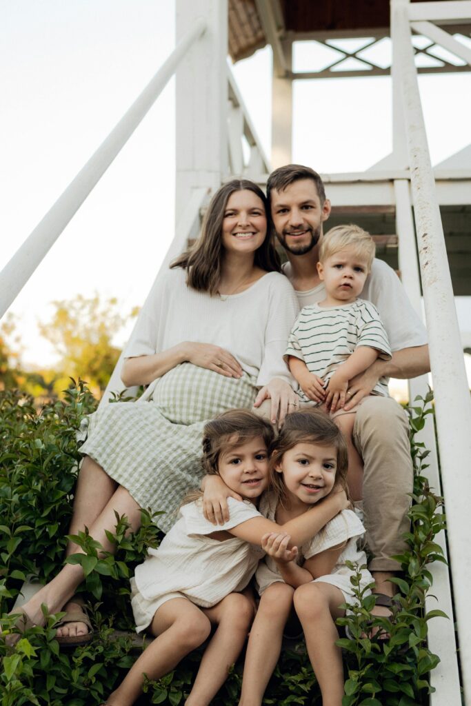 A joyful family with three children sitting on outdoor steps, basking in a warm summer day.