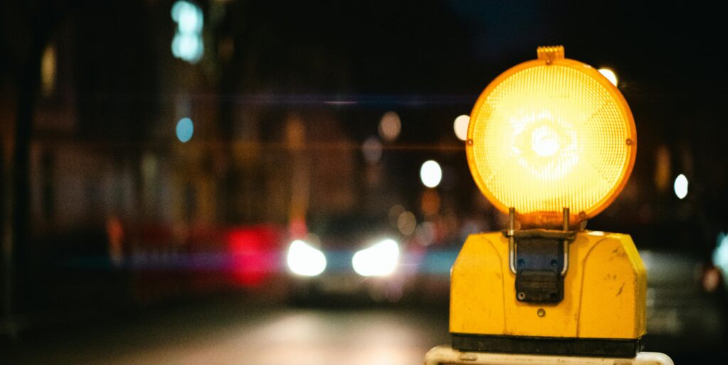 A night scene showing a bright yellow traffic warning light in an urban setting.
